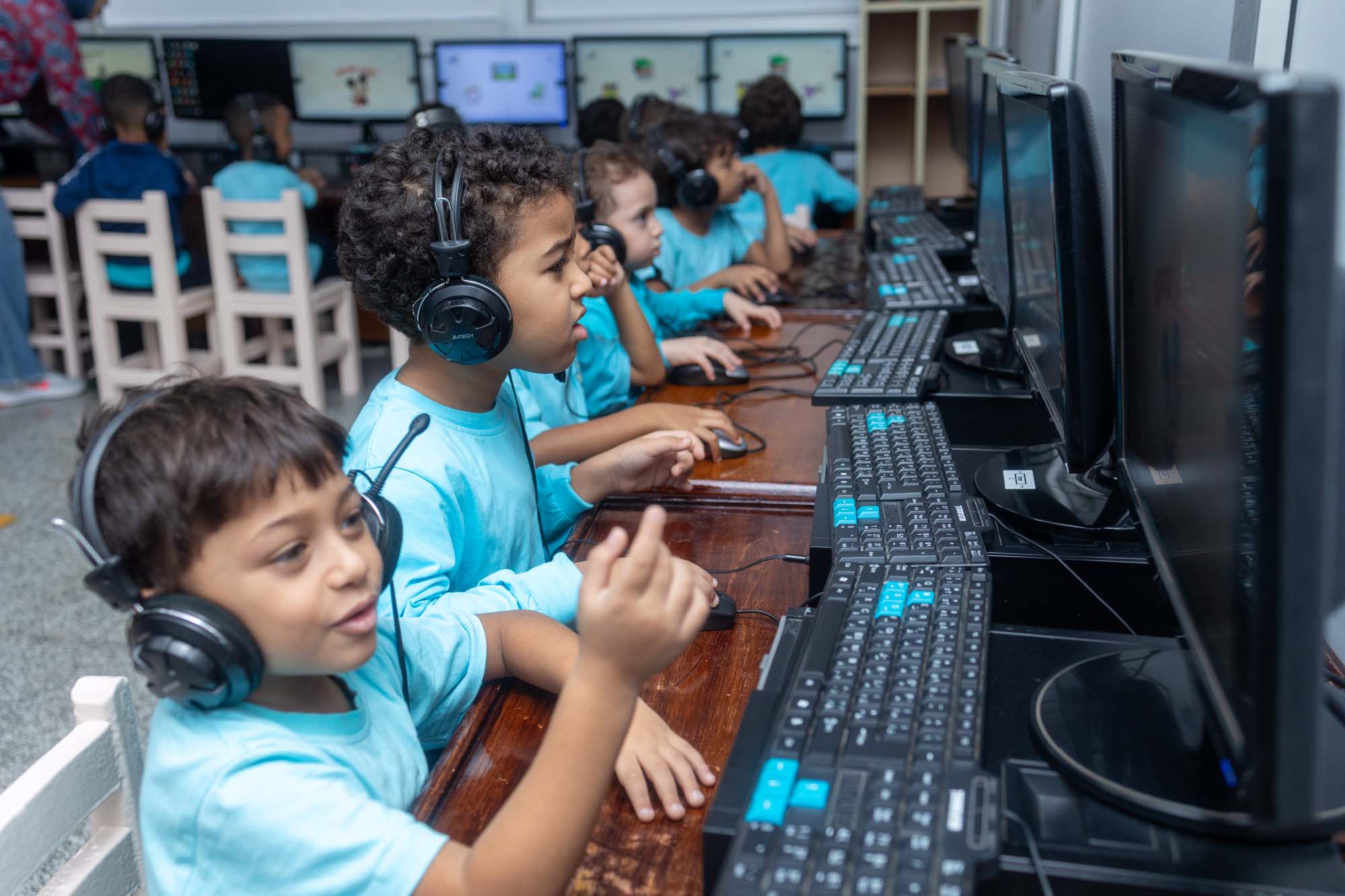Kindergarten children using computers and headphones at OLS