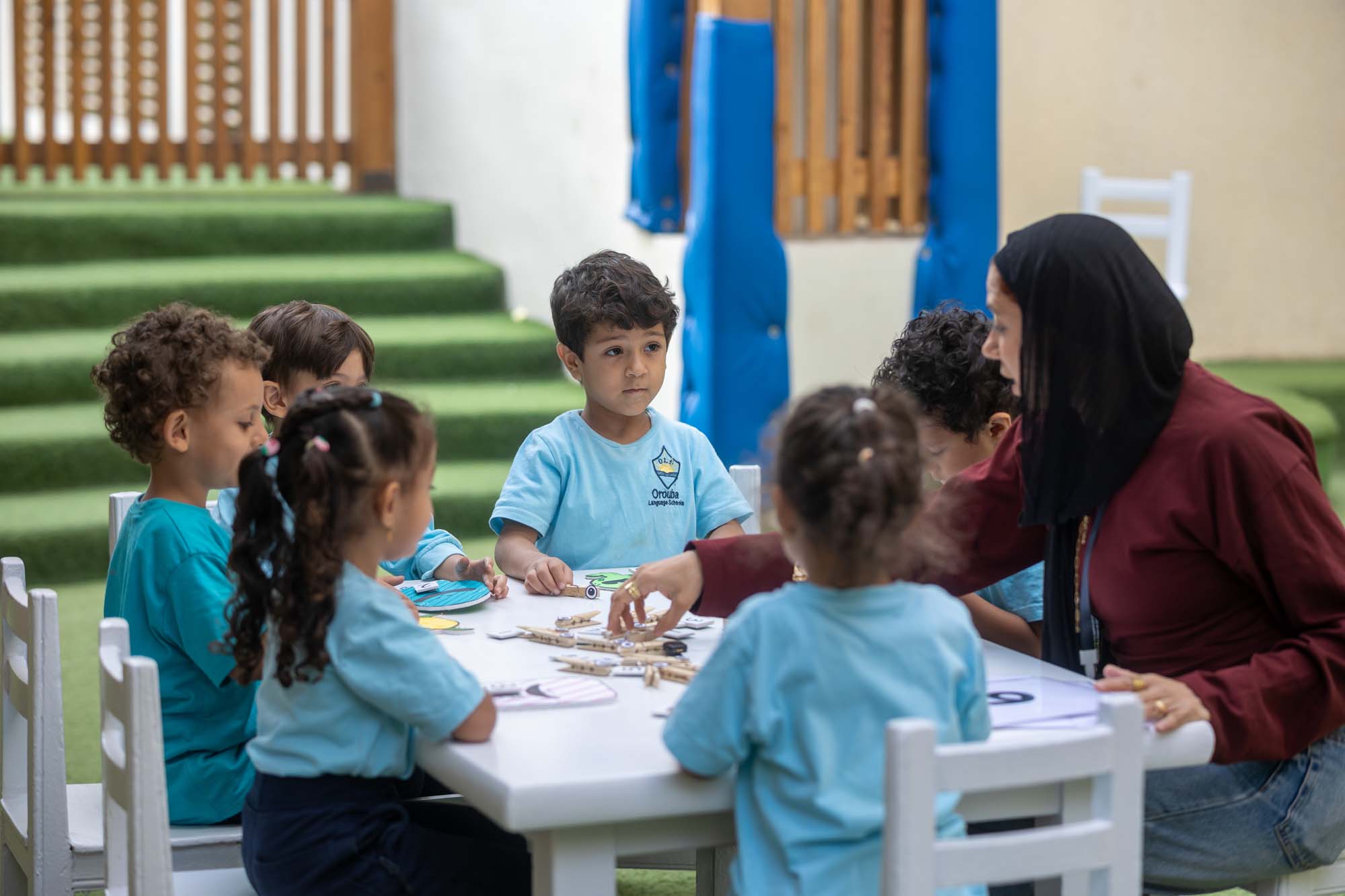 An OLS teacher supporting kindergarten children around an activity table