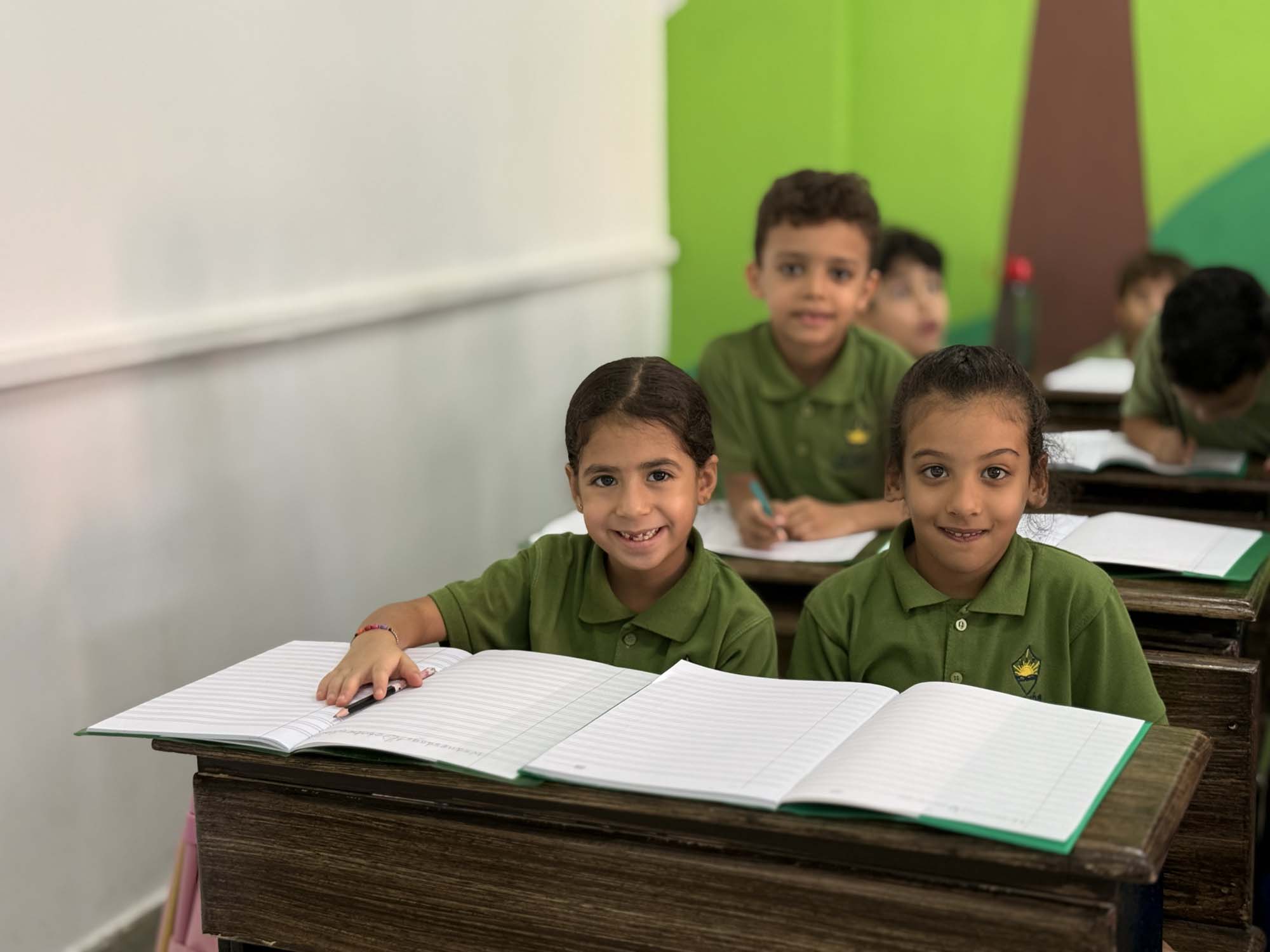 Primary children with open exercise books in their classroom