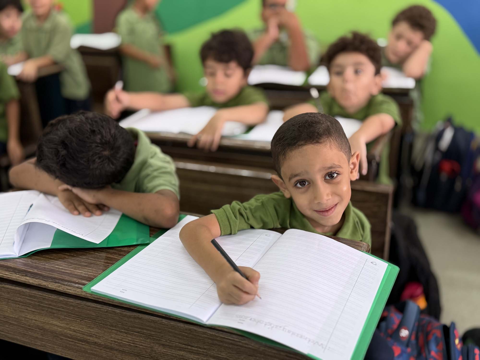 A primary pupil smiling while completing classroom work
